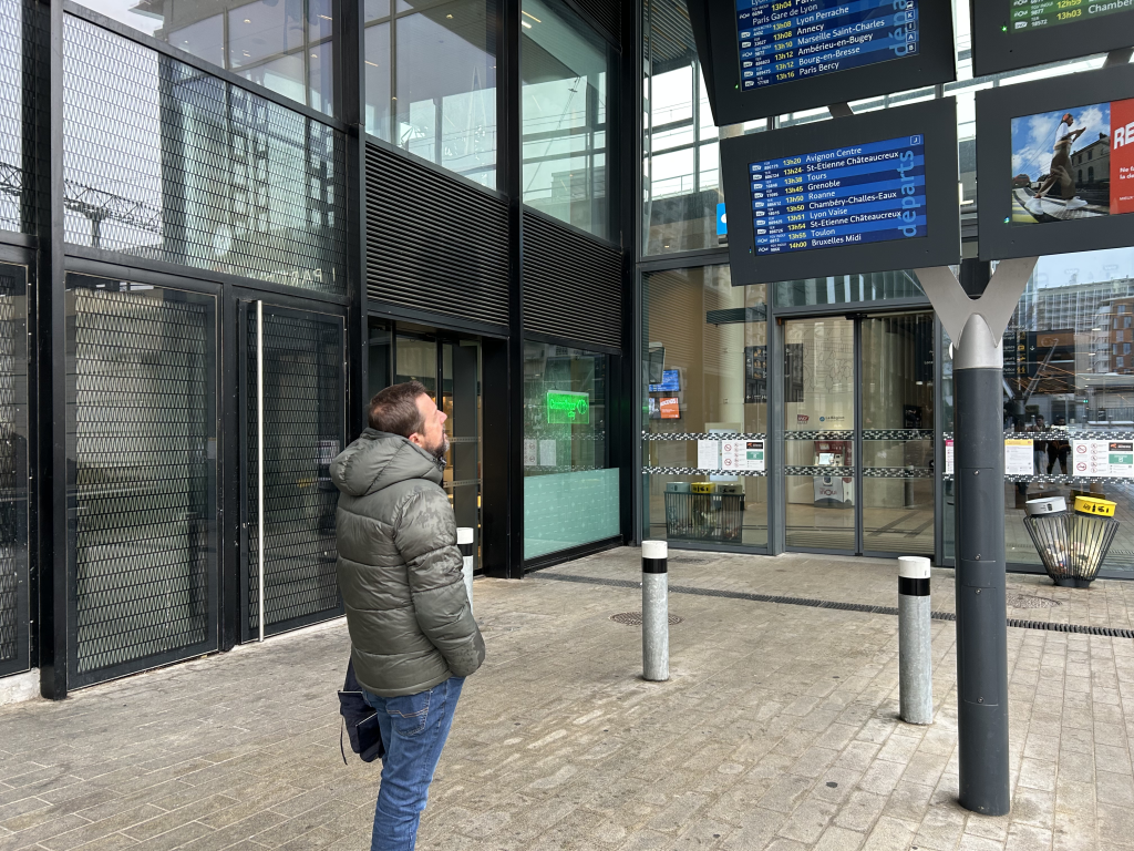 Samuel Carrier consultant l'horaire de son train sur le tableau de la SNCF.
