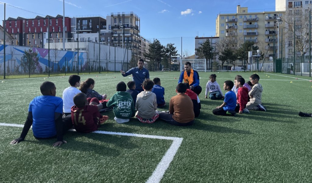 Deux éducateurs, encadrant un groupe de jeunes sur un stade de foot en plein Vénissieux